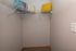 Cozy walk-in closet with a sturdy wire shelf, accented by a vibrant yellow pillow and a soft, patterned blanket.