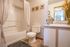 Chic bathroom with elegant tile flooring, decorative wall art, and a stylish vanity with modern fixtures.