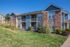 Charming apartment building with brick and siding exterior, featuring private balconies and lush landscaped surroundings.