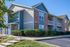 Charming suburban apartment building with modern design, featuring brick and siding exterior, lush landscaping, and spacious balconies.