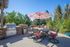 Tranquil outdoor patio featuring a stylish dining set with a striped umbrella, surrounded by lush greenery and a modern BBQ grill, perfect for entertaining.
