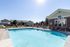 Inviting outdoor pool area with sun loungers and charming clubhouse, perfect for relaxation and social gatherings.