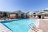 Inviting outdoor pool area with modern lounge chairs and a charming clubhouse, perfect for relaxation and leisure.