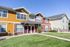 Charming two-story townhouse with colorful siding, featuring large windows and a welcoming front garden.