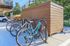 Modern apartment amenity with a convenient bike rack and secure parking, surrounded by lush greenery for an active lifestyle.