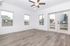 Bright and airy living space with modern wood flooring, large windows, and a ceiling fan, showcasing a serene outdoor view.