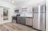 Modern kitchen with sleek stainless steel appliances, elegant cabinetry, and a bright open layout featuring contemporary wood flooring and glass door access to the outdoors.