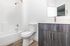 Modern bathroom featuring sleek wood cabinetry, pristine white surfaces, and stylish fixtures.