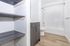 Modern bathroom featuring sleek gray cabinetry, elegant shelving, and a pristine shower-tub combination with light wood flooring.