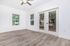 Bright and airy living room with modern wood flooring, ceiling fan, and double French doors leading to a balcony with a serene view.