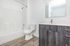 Contemporary bathroom with sleek fixtures, a polished vanity, and elegant wood flooring.