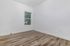 Bright and inviting room with sleek wood flooring and a large window offering a serene outdoor view.