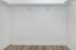 Spacious walk-in closet with sleek white walls and elegant wooden flooring, perfect for ample storage.