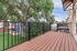 Inviting balcony with elegant wood flooring and sleek metal railings, offering picturesque views of lush greenery and a serene outdoor setting.