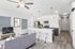 Modern open-plan apartment interior featuring a sleek kitchen with stainless steel appliances, elegant bar stools, and a chic living area with a stylish gray sofa.