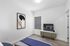 Modern bedroom with chic abstract artwork, sleek wooden flooring, and a cozy TV setup for a stylish retreat.