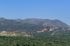 Spectacular panoramic view of lush green valleys and rugged mountain ranges under a clear blue sky, ideal for nature enthusiasts and adventure seekers.