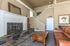 Elegant living room with high ceilings, a classic fireplace, and a cozy leather sofa. Features stylish decor and ample natural light.