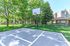 Inviting apartment complex with lush green landscaping and a basketball court, ideal for active outdoor recreation.