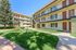 Charming apartment complex with inviting green spaces, outdoor seating, and modern three-story design.