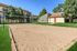 Inviting outdoor sand volleyball court surrounded by lush green lawns and charming apartments, perfect for leisure and community fun.