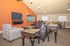 Elegant living room with rich wood furnishings, patterned armchair, and inviting dining area, perfect for comfortable gatherings.
