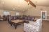 Elegant living room with plush leather sofas, ornate coffee tables, and stylish dining area under a high ceiling with modern pendant lighting.