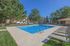 Inviting outdoor pool area with sun loungers and vibrant green surroundings, perfect for relaxation under the blue sky.