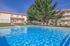 Inviting apartment complex featuring a sparkling outdoor pool surrounded by lounge chairs and lush green trees, perfect for relaxation.