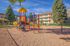 Charming apartment exterior with a vibrant playground, surrounded by lush greenery and inviting outdoor spaces.