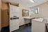 Bright laundry room with stacked washer and dryer units, folding table, and scenic window view.