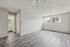 Bright and airy living space with modern flooring, large windows, and a glimpse into a chic bathroom.