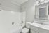Sleek and modern bathroom with a pristine white bathtub, stylish vanity, and bright mirror lighting, creating a serene and inviting atmosphere.