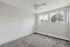 Bright and inviting bedroom with plush carpeting, large windows offering serene views, and a sleek ceiling fan.