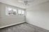 Bright, spacious bedroom with plush carpet, large windows, and ceiling fan offering natural light and comfort.