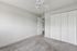 Bright and airy bedroom with plush carpeting, white closet doors, and a ceiling fan for comfort.