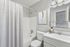 Inviting bathroom with a sleek design, featuring a modern shower-tub combo, elegant decor, and a large mirror enhancing spaciousness.