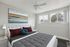 Bright and airy bedroom with contemporary decor featuring a plush bed, vibrant artwork, and large windows offering scenic views.