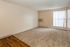 Bright, spacious room with cozy carpet flooring, large window with vertical blinds, and efficient wall-mounted air conditioning.