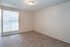 Bright, cozy bedroom with plush carpeting and natural light from large windows.