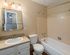Inviting bathroom featuring a stylish vanity with mirror, warm lighting, and a modern bathtub perfect for relaxation.
