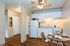 Charming kitchen with modern white cabinets, cozy dining area, and elegant wood flooring, perfect for stylish living.