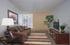Inviting living room with cozy brown sofa, vibrant striped rug, and elegant decor, featuring a modern entertainment unit and lush greenery.