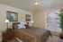 Charming bedroom with elegant decor, featuring cozy bed, stylish lamps, and vibrant natural light through large window blinds.