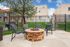 Inviting outdoor patio area with cozy fire pit, modern lounge chairs, and lush greenery, perfect for relaxation and social gatherings.
