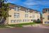 Sunlit apartment building with charming windows, surrounded by lush greenery and vibrant landscaping.