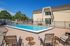 Inviting outdoor pool area with lounge chairs, perfect for relaxation and enjoying sunny days, featuring a charming building and landscaped surroundings.
