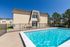 Inviting apartment building with a sparkling outdoor pool, perfect for relaxation and leisure, set against a clear blue sky.