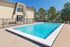 Charming outdoor pool area with crystal clear water, surrounded by a secure fence and lush greenery, perfect for relaxation and enjoyment.
