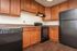 Modern kitchen featuring sleek black appliances, warm wooden cabinetry, and elegant countertops.